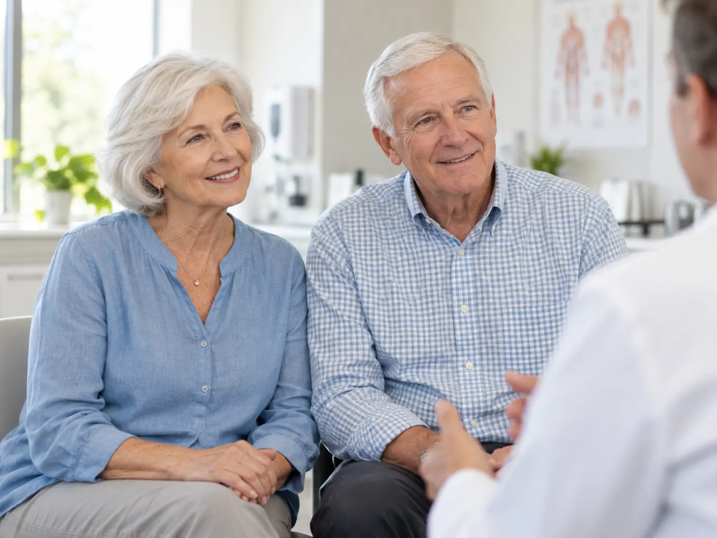 An older white couple meeting with a caring clinician in a bright clinic